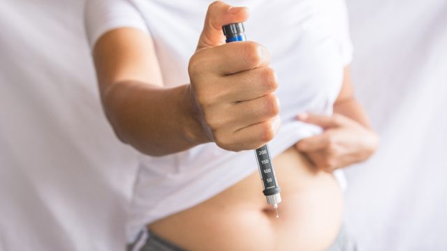 woman holding out weight-loss drug pen
