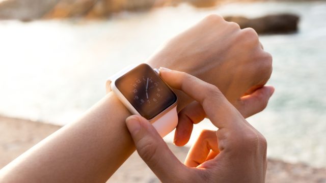 closeup of a female hand adjusting a pink apple watch outside