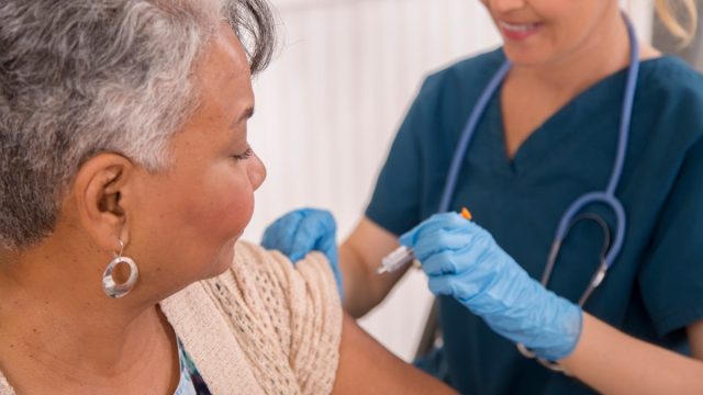 female nurse giving a vaccine to a mature woman