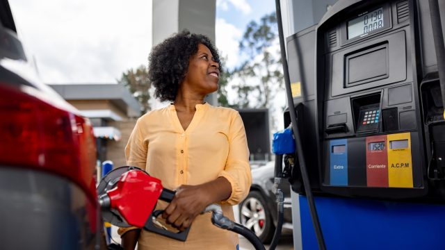 A woman filling up her car with gas at a station
