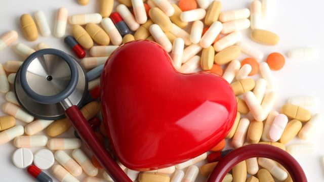 pile of pills and supplements with a red heart and stethoscope