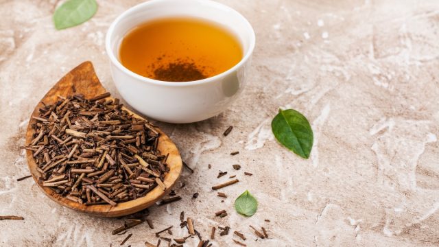 hojicha leaves next to a cup of hojicha tea