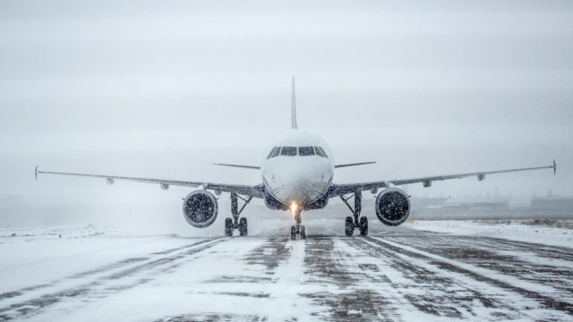 Airliner on runway in blizzard. Aircraft during taxiing during heavy snow. Passenger plane in snow at airport. Modern twin-engine passenger airplane taxiing for take off at airport during snow blizzard