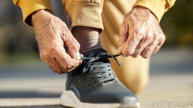 A close up of a senior person tying their shoes